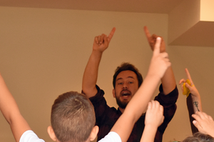 Magnus Landsberg zeigt mit seinen Fingern in die Luft, umgeben von Kindern