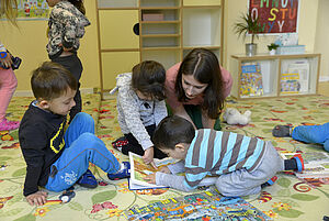 Eine Erzieherin liest mit mehreren Kindern ein Buch