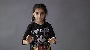 Ein Mädchen streckt beide Hände vor sich mit nach unten gerichteten Handflächen