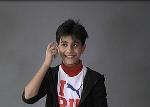 Ein Junge tippt sich mit dem Zeigefinger an die Schläfe
