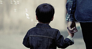 Ein Junge hält die Hand einer erwachsenen Person