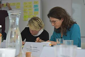 Zwei der eingeladenen Expertinnen, Svetlana Vishek und Galina Putjata, sitzen am Tisch und sind intensiv in ihre Arbeit vertieft