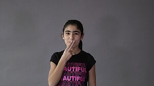 Ein Mädchen legt Zeigefinger und Mittelfinger auf die Lippen