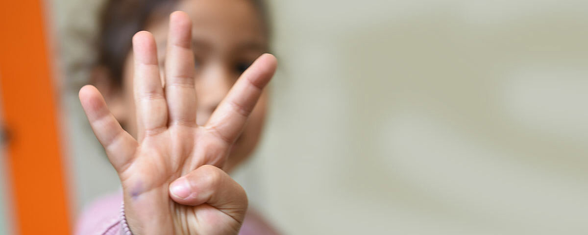 Ein Kind hält vier Finger in die Kamera