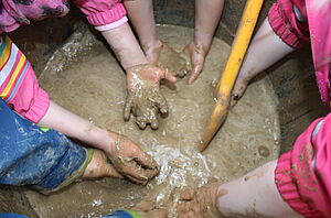 Kinder vermischen Lehm und Wasser.
